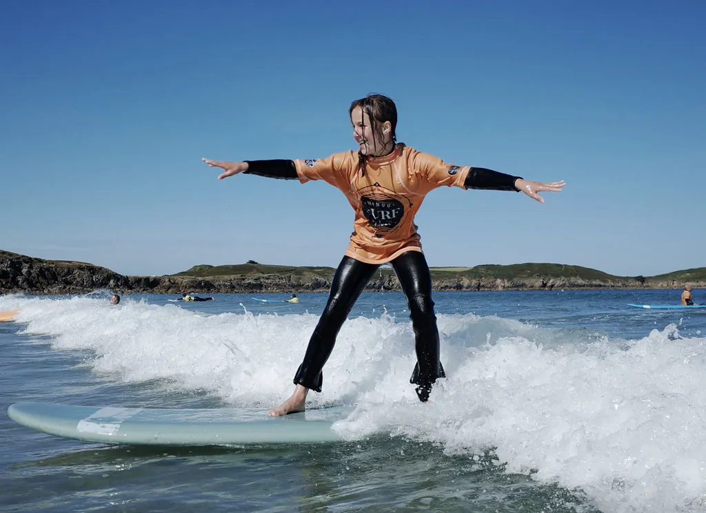 Jeune surfeuse debout sur sa planche lors d'un cours de la Minou Surf School